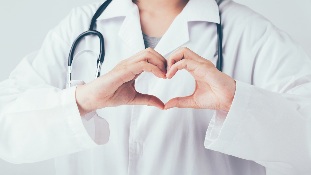 femme avec blouse de médecin faisant un coeur avec ses mains